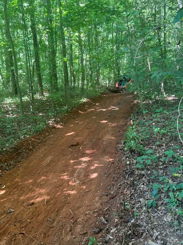 Clean, graded red-clay drive through the woods