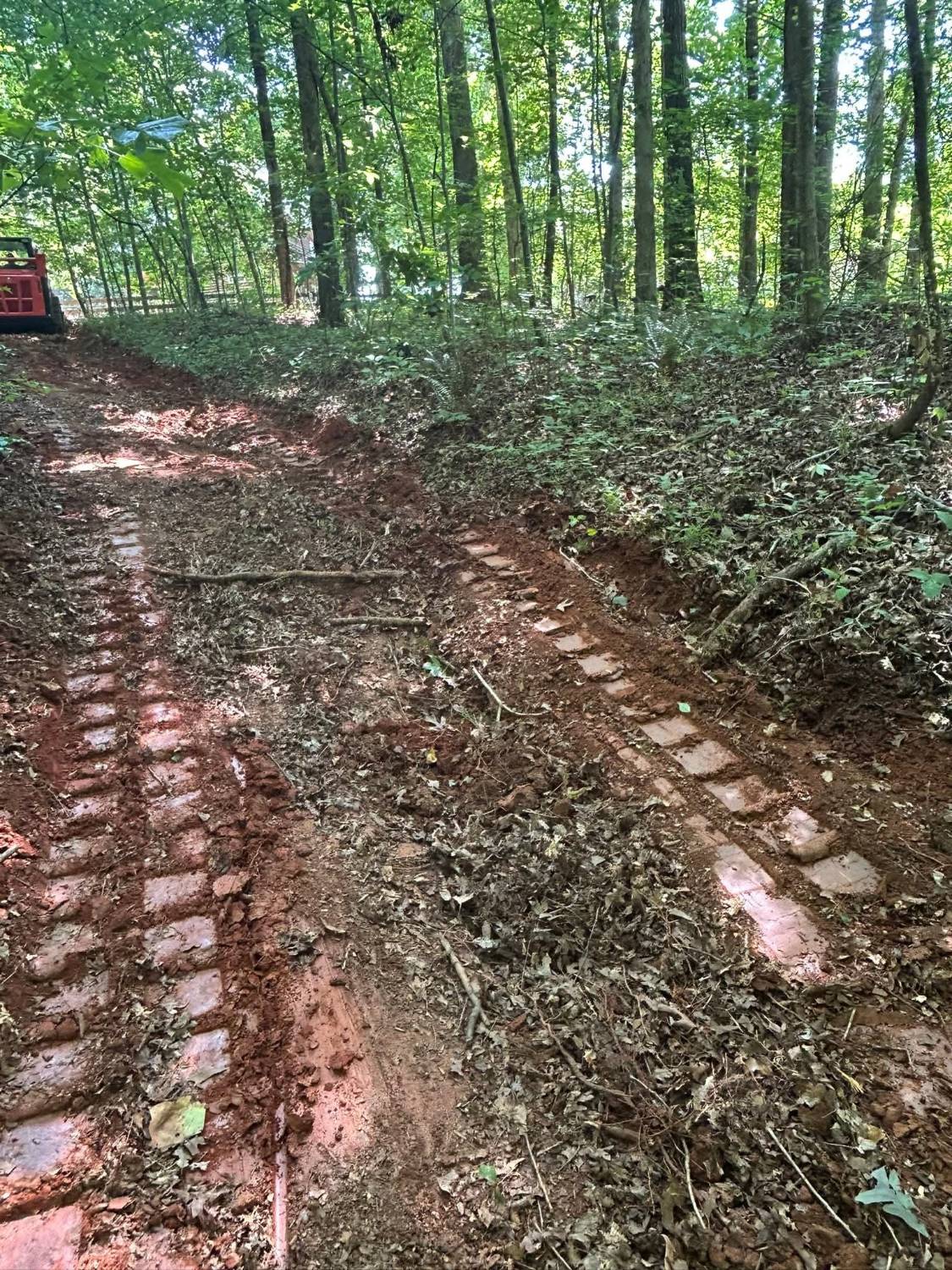 Digging in: fresh track marks in the red clay, with the machine in the background